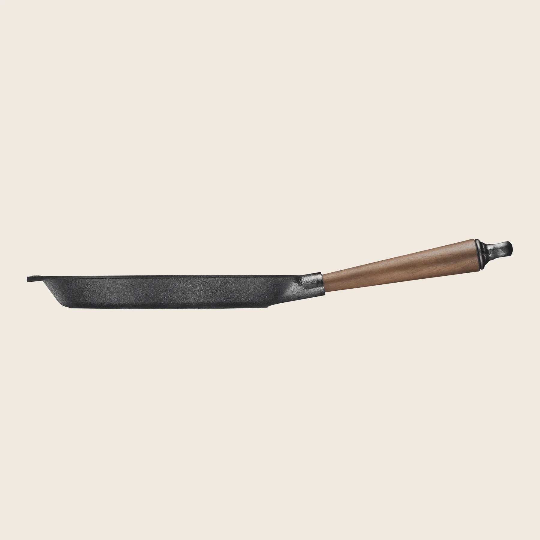 A 10 Skeppshult cast iron skillet with a walnut handle, captured from the side on a plain background.