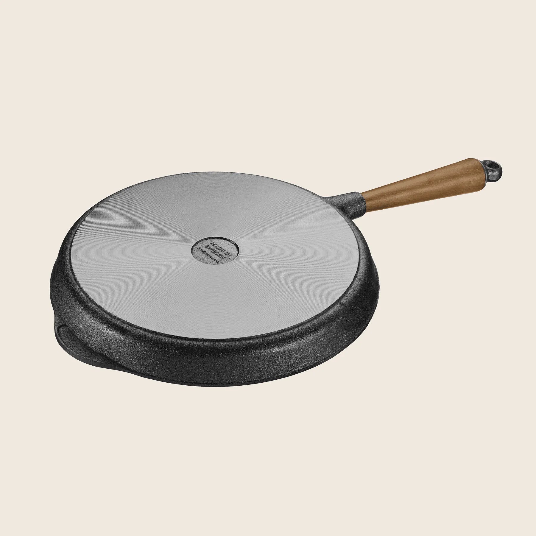 The Skeppshult Grill Pan With Walnut Handle, 11/28 cm, showcases a non-stick surface and a round, flat metal lid with a walnut handle, all elegantly set against a light background.