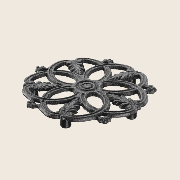 The Skeppshult Cast Iron Trivet, expertly handcrafted in Sweden, showcases an ornate, symmetrical floral design.