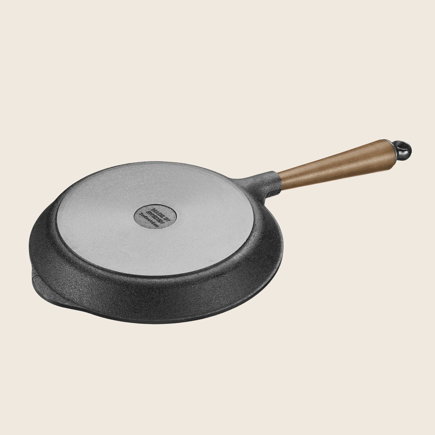 The Skeppshult 9.5 Skillet with a walnut handle is shown upside down on a plain background, highlighting its excellent heat conduction.