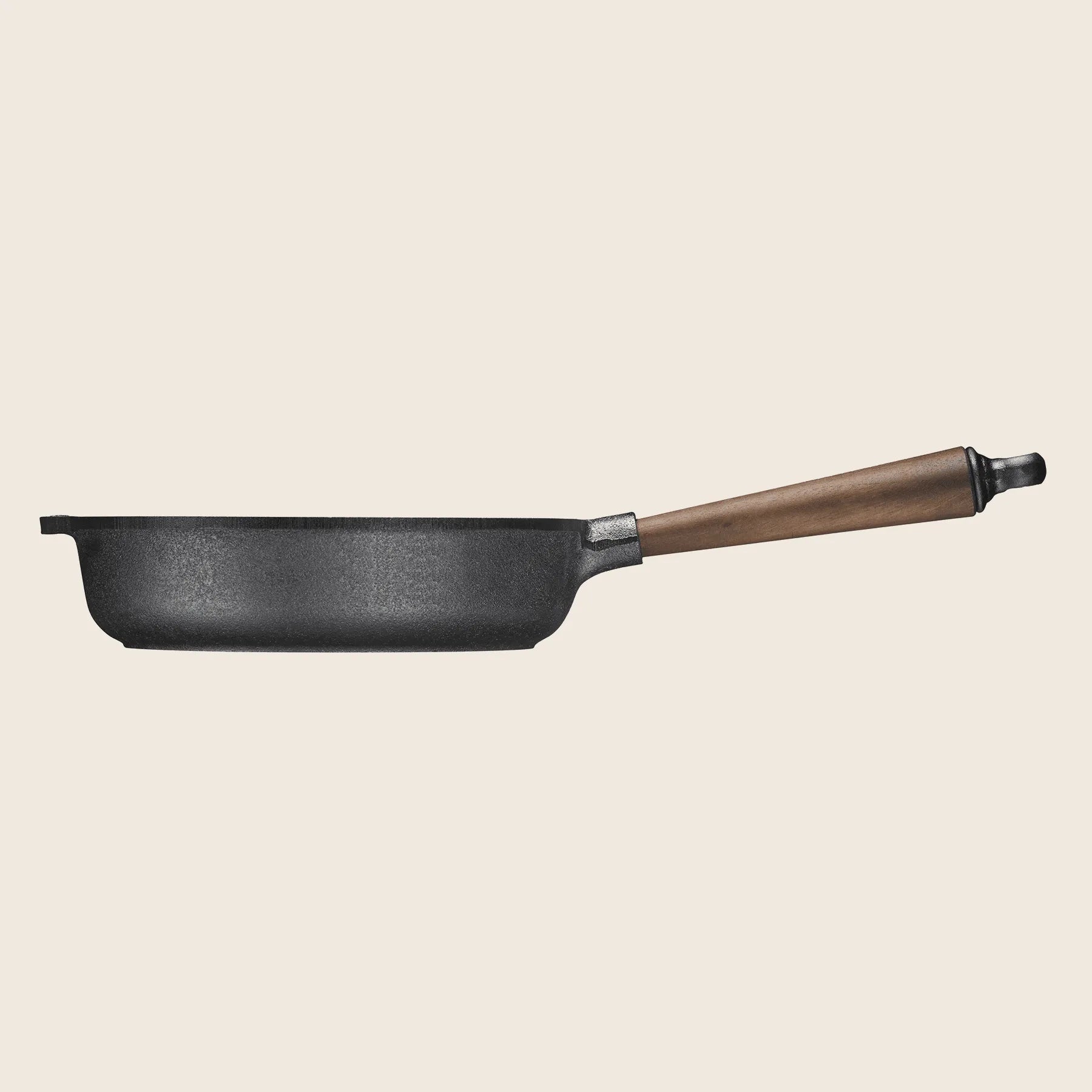 A Skeppshult 9.75 deep cast iron skillet with a walnut handle, handcrafted in Sweden, is shown from the side against a neutral background.