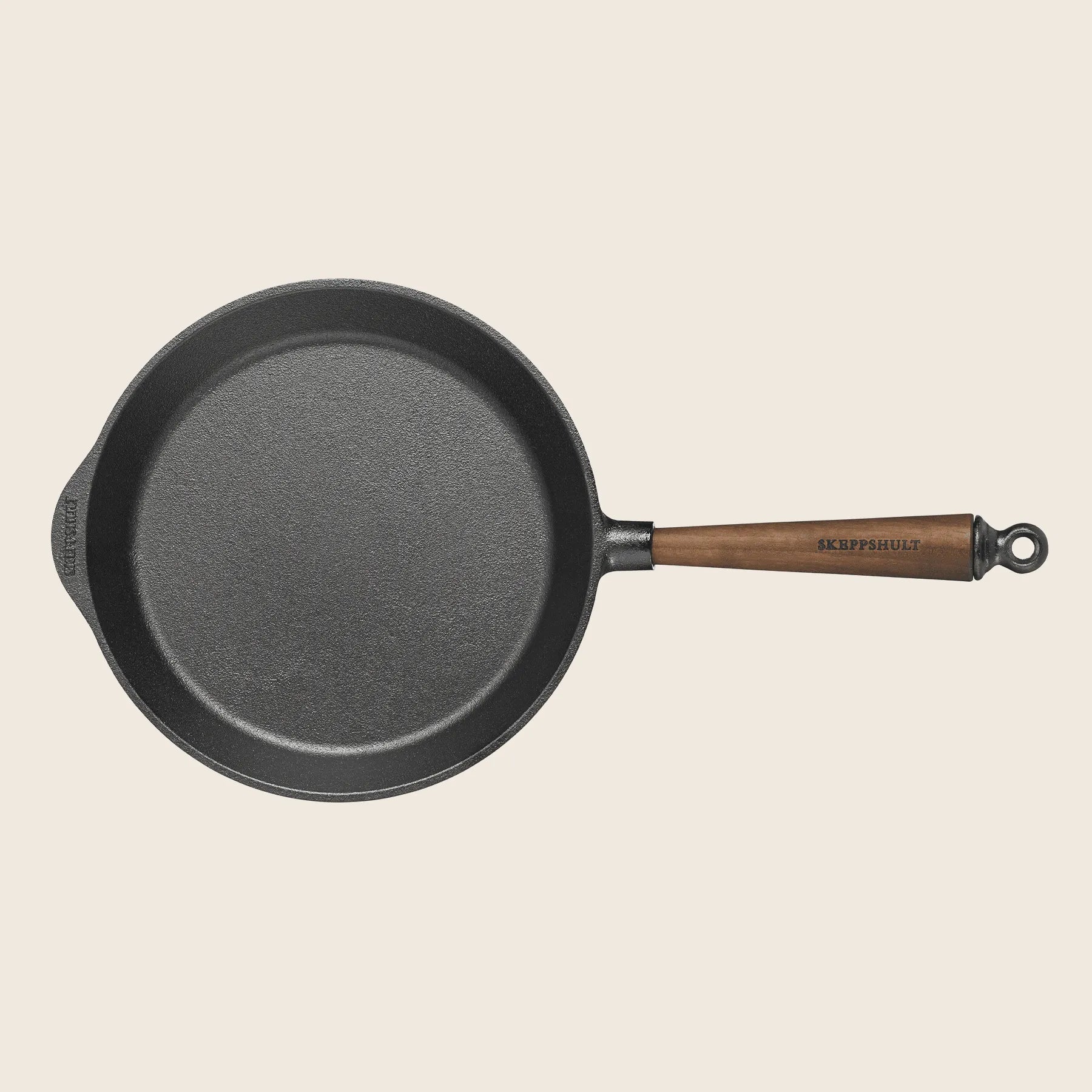 The Skeppshult 10 cast iron skillet boasts a non-stick surface, a walnut handle with a hanging loop, and a small pouring spout for style and convenience in your kitchen.