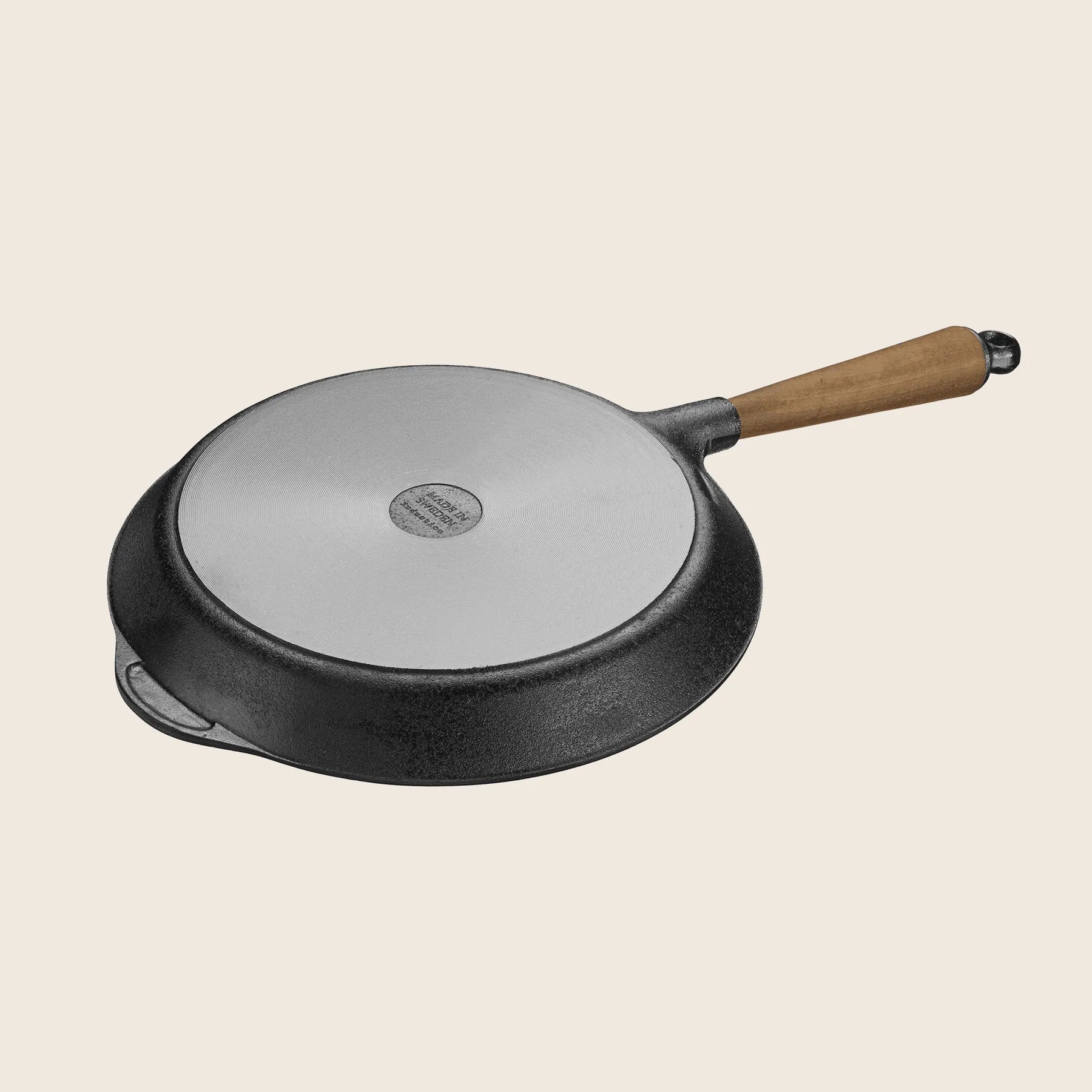 The Skeppshult Skillet with an 11 walnut handle and fitted lid rests on a light background, famed for its superior heat conduction.