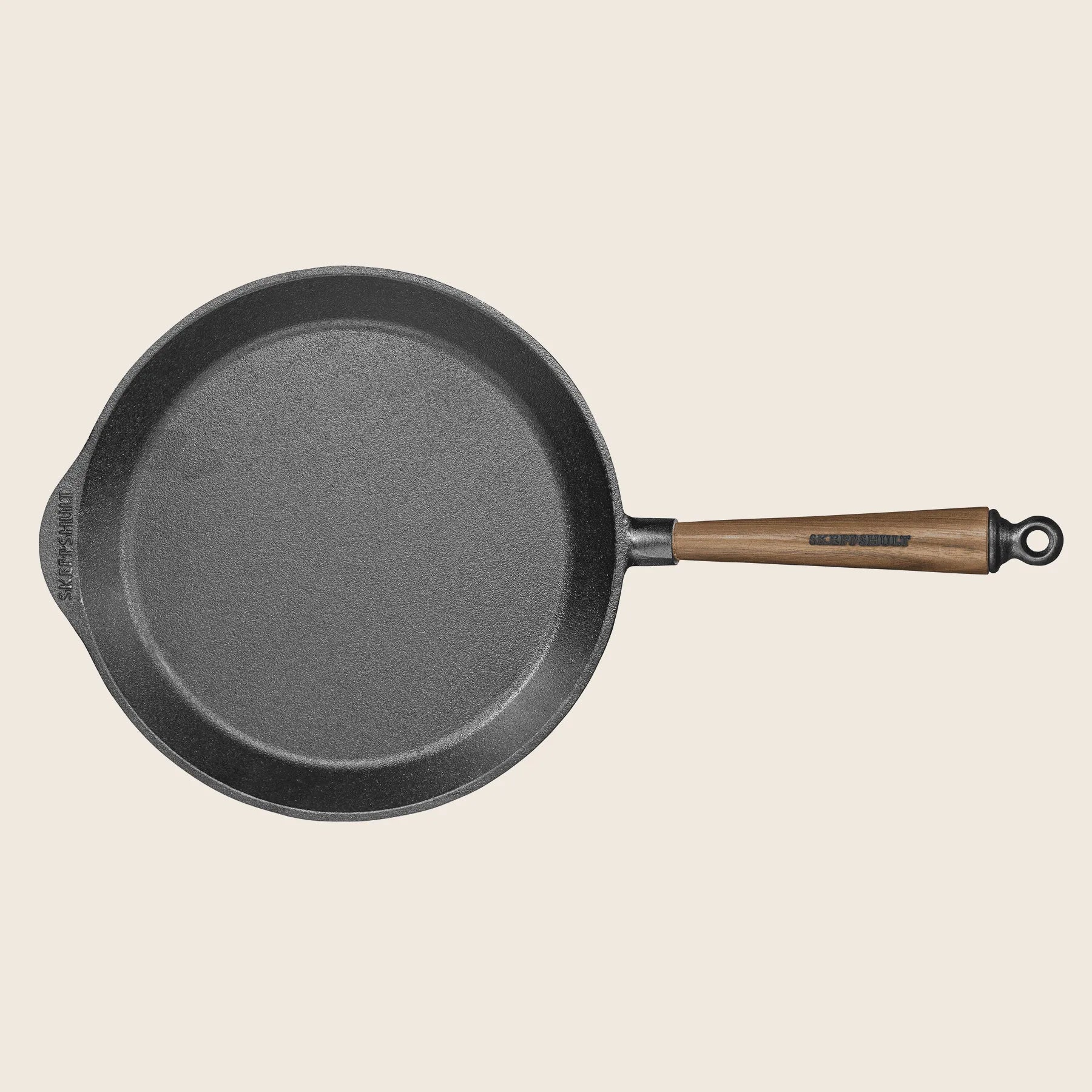 The Skeppshult Skillet with Walnut Handle, 11/28 cm, is beautifully crafted with a round design in black walnut. It features a non-stick surface, superior heat conduction, a wooden handle, and a small pouring spout.