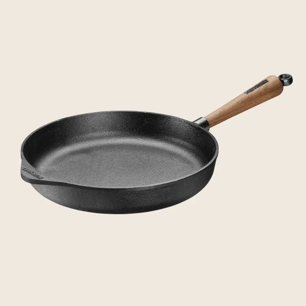 The Skeppshult Deep Skillet with an 11 walnut handle sits on a light backdrop, highlighting its non-stick surface. Handcrafted in Sweden, this cast iron piece balances functionality and elegance.