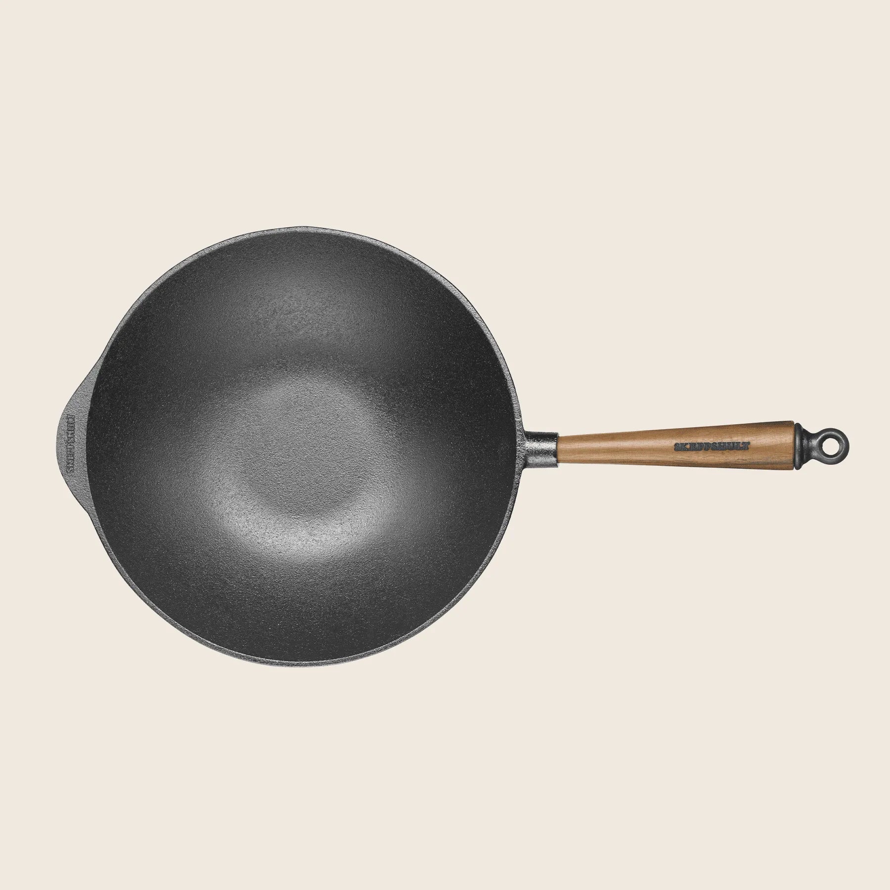 A Skeppshult 12.2 black cast iron wok with a walnut handle, handcrafted in Sweden, is shown against a plain background from above.