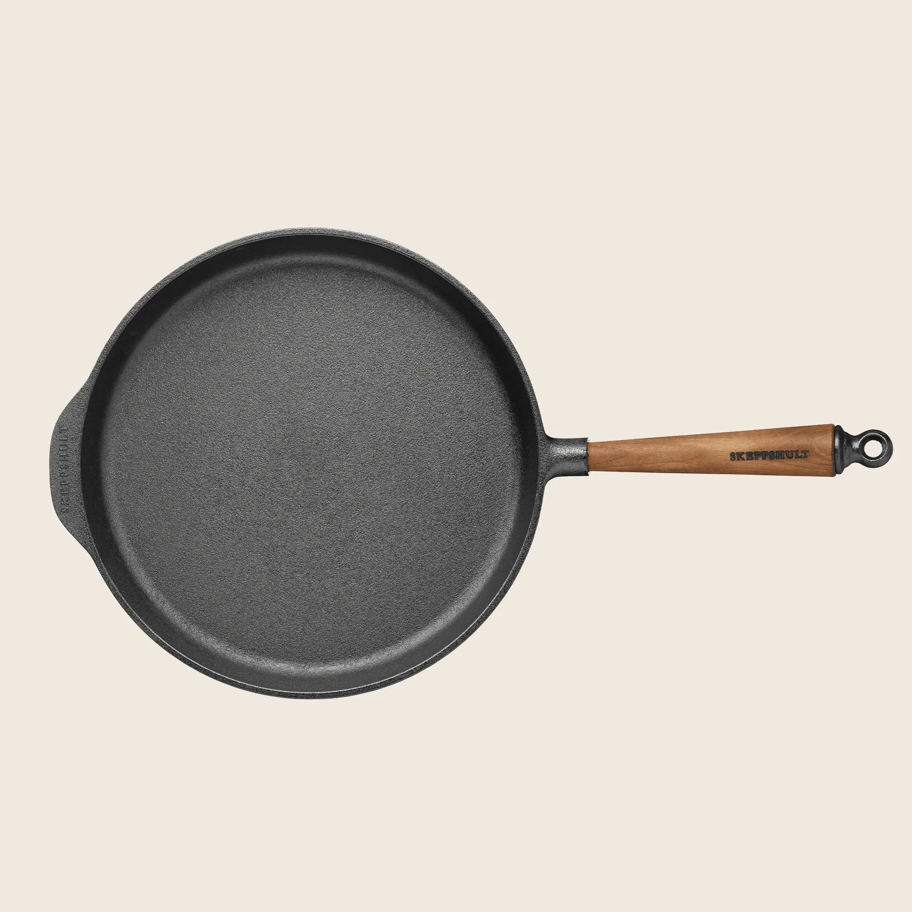 The Skeppshult Deep Skillet is a round, black 11.8 cast iron pan with a non-stick surface and a walnut handle, handcrafted in Sweden. It includes a side pouring spout and is presented against a plain background.