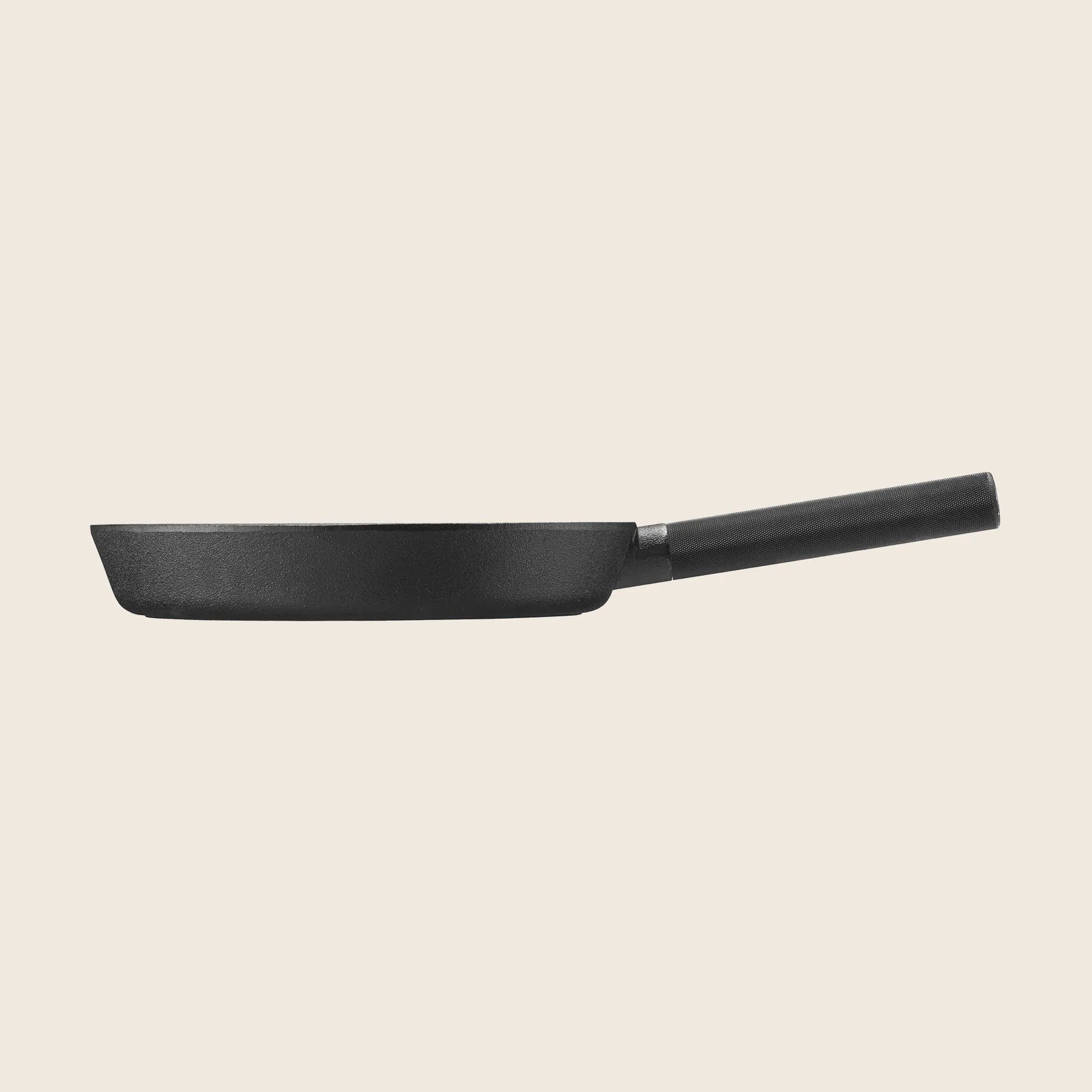 Side view of the Skeppshult Skillet 11 / 28 cm, a handcrafted black frying pan from Sweden with a long handle and non-stick surface, isolated on an off-white background.