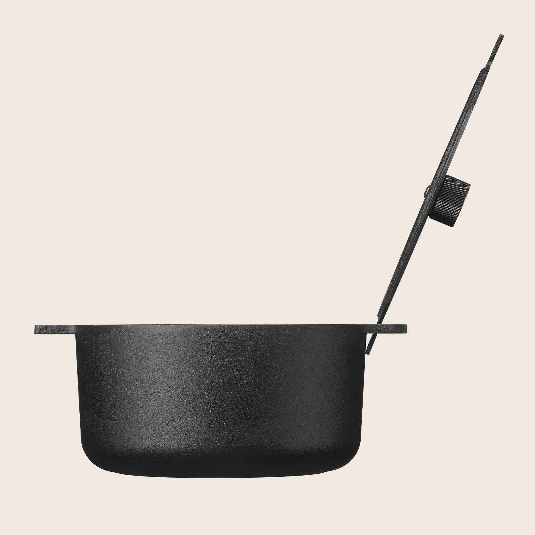 A side view of the Skeppshult Black Dutch Oven with a partially open cast iron lid is shown against a plain background, its finish gleaming and seasoned with organic canola oil. Capacity: 5.25 qt (5 L).