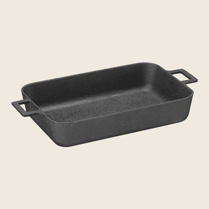 The Skeppshult Oven Dish, a precision-crafted rectangular black cast iron baking dish, features side handles and is pre-seasoned with organic canola oil for an easy cooking experience.