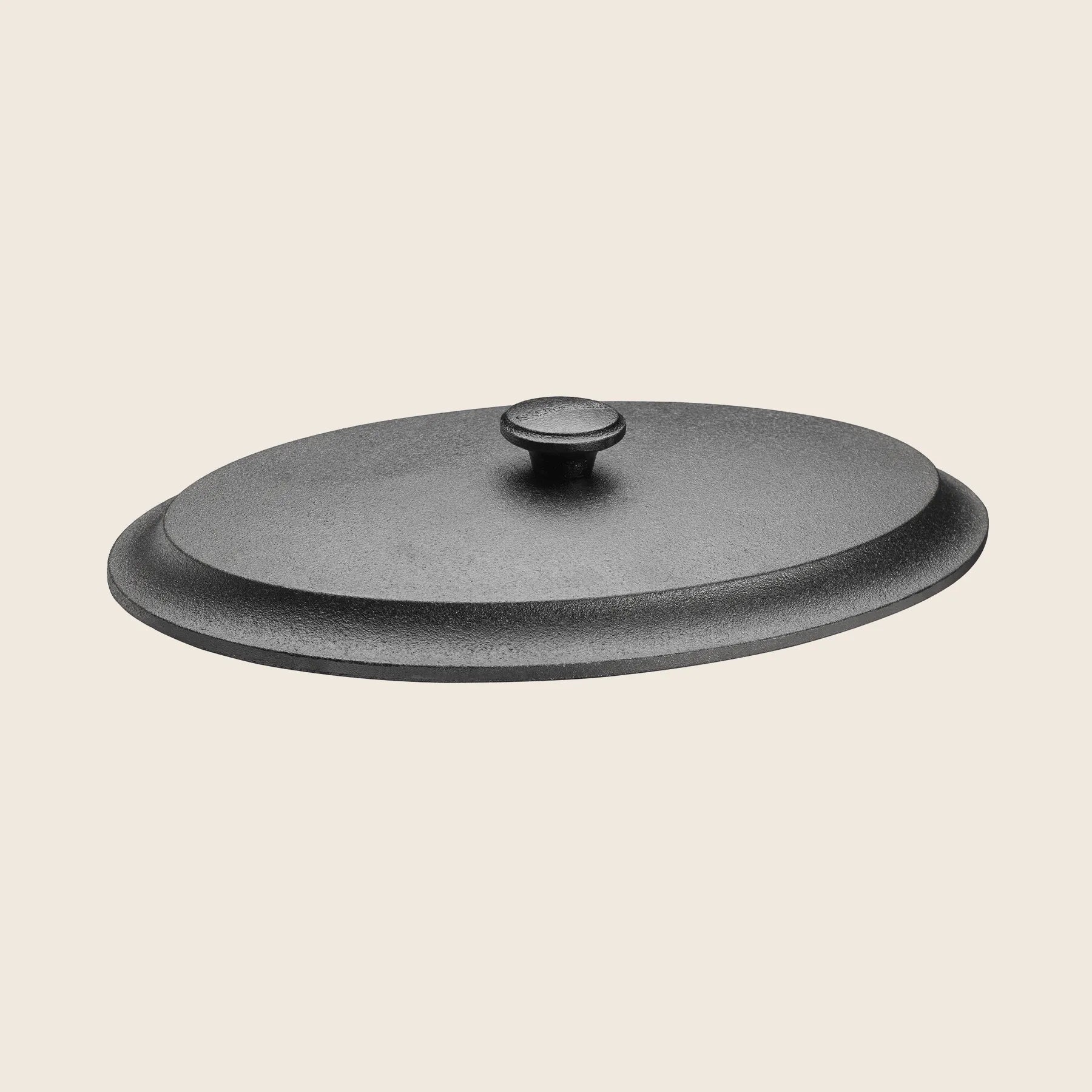 The black cast iron lid of the Skeppshult Oval Dutch Oven (6.3 qt / 6 L) rests against a plain light background, ensuring even heat distribution for your culinary creations.