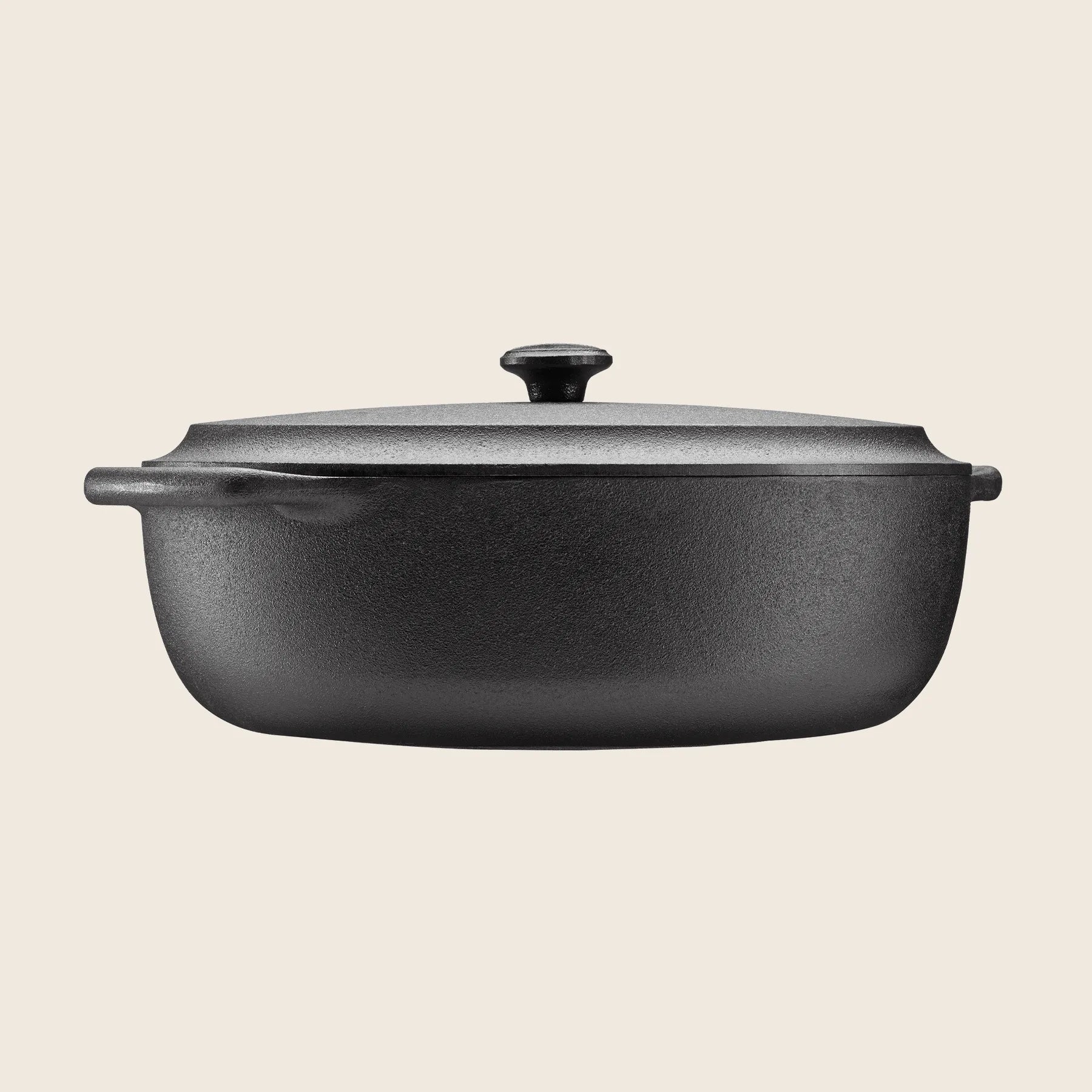 A black, oval-shaped Skeppshult cast iron Dutch oven, 6.3 qt/6 L with a lid and two handles, sits against a plain background, ensuring even heat distribution for optimal cooking results.