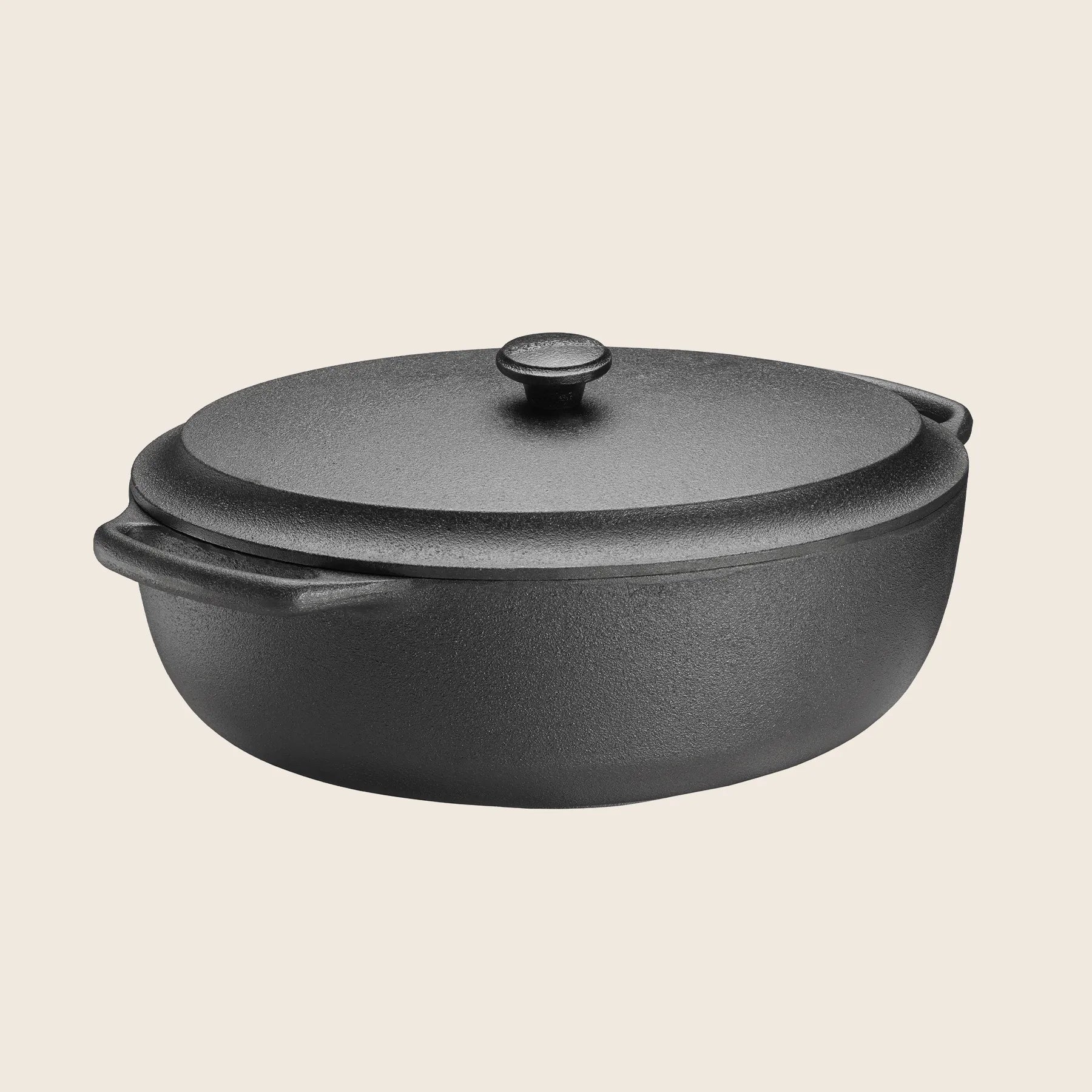 The Skeppshult Oval Dutch Oven, a 6.3 qt black cast iron pot with a matching lid and side handles, elegantly rests against a plain background, ensuring even heat distribution.