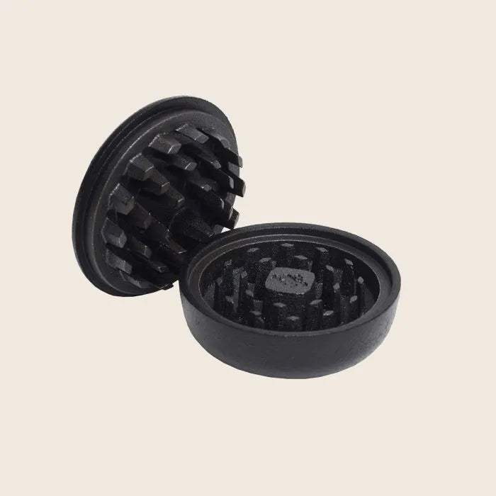 An open Skeppshult Spice Grinder, crafted with durable cast iron, reveals its sharp internal teeth while resting elegantly on a plain background.