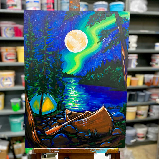 The vibrant scene depicted in "Sparkle," an artwork by Adam Turman, captures a nighttime lake with a canoe and tent under the dazzling aurora and full moon. The archival pigment inks breathe life into this piece on fine art paper prints, showcased beautifully on an easel within a paint-supplied studio.