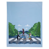 This vibrant illustration by Adam Turman adorns the "Tea Towel: MN Abbey Road," showcasing four dog-like characters strolling across a forest road in a nod to the iconic Abbey Road scene. This beautifully captured image is printed on a machine washable cotton towel, making it an ideal creative addition to any home.