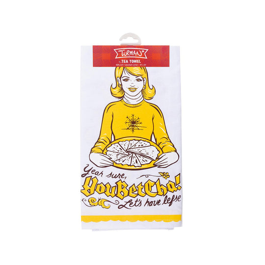 The Tea Towel: Yeah, Sure, You Betcha! Lets have Lefse! by Adam Turman features a charming print of a woman holding a pie alongside the text.