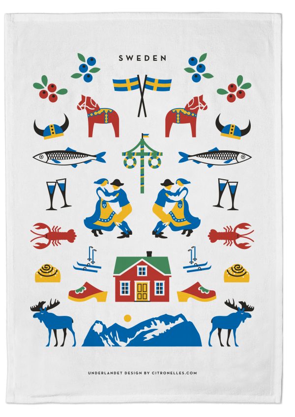 The Tea Towel: Sweden Traditions boasts a vibrant Swedish-themed illustration with horses, Viking helmets, dancing figures at a midsummer pole, fish, lobsters, and moose on skis near a house and mountains. Crafted in Sweden from eco-friendly materials.