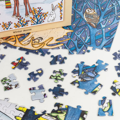 Jigsaw puzzle pieces with images of owls, a rabbit, and colorful patterns are scattered on a white surface.
