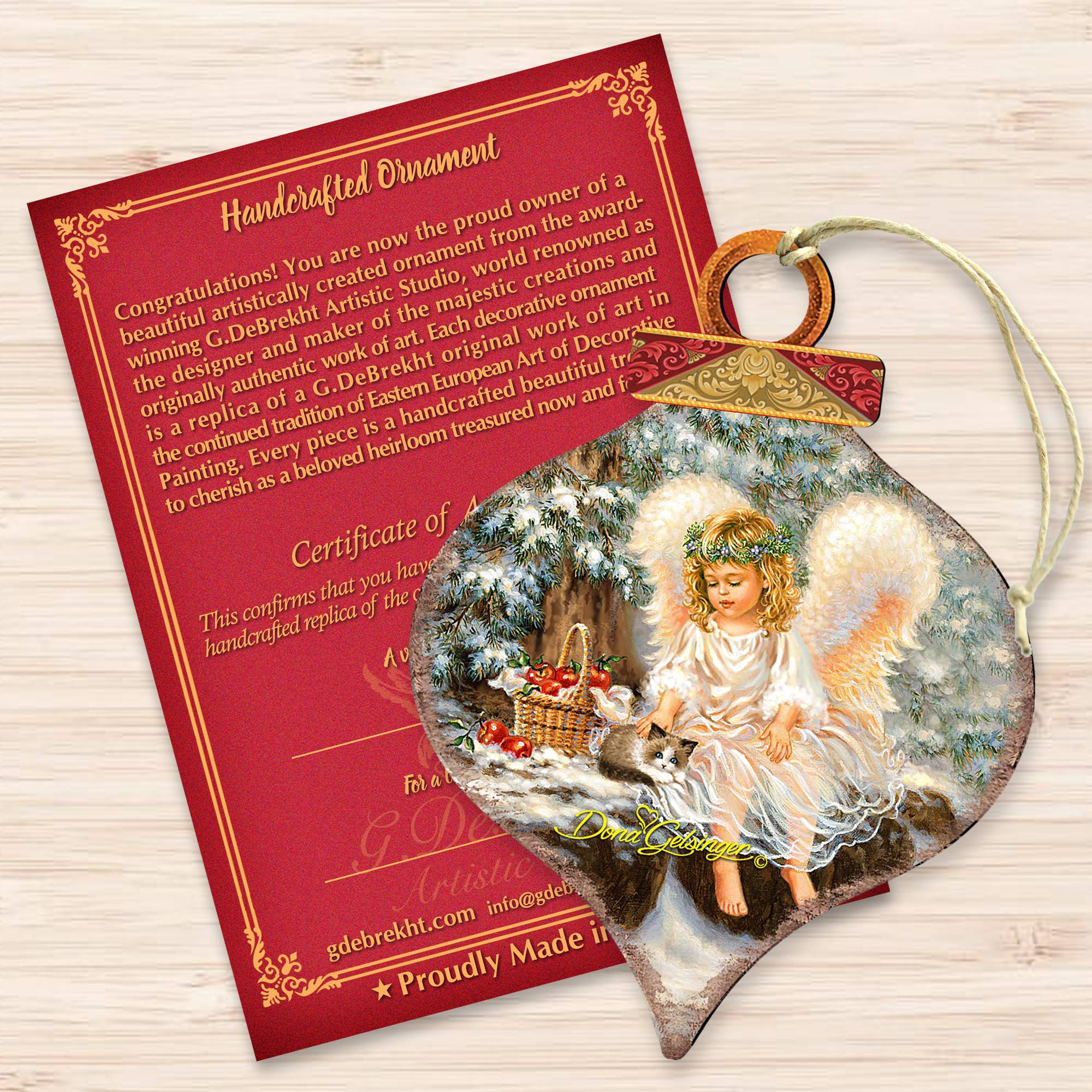 This beautifully handcrafted angel-themed ornament, known as the ANGEL CARDINAL Wood Ornament from G.DeBrekht Artistic Studios, comes with a certificate and features a snow scene of a cherubic angel sitting with a basket and lamb against a red background. This piece combines beauty and weather resistance for any setting.