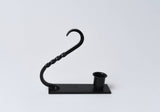 Black iron taper holder with a twisted handle, cylindrical candle cup, and rectangular base.