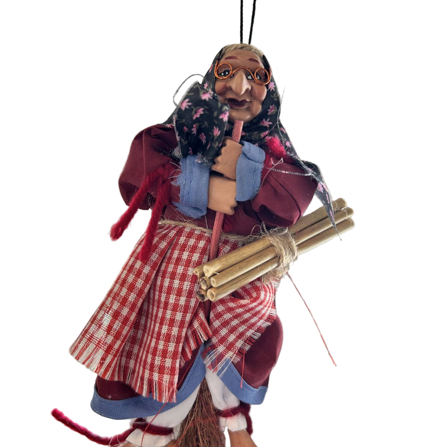 The Decor: Kitchen Witch Doll – Opalina Red (8.3" Tall) features glasses, a headscarf, and a red plaid skirt, holding sticks and a broom—capturing Northern European hearth magic—against a plain white background.