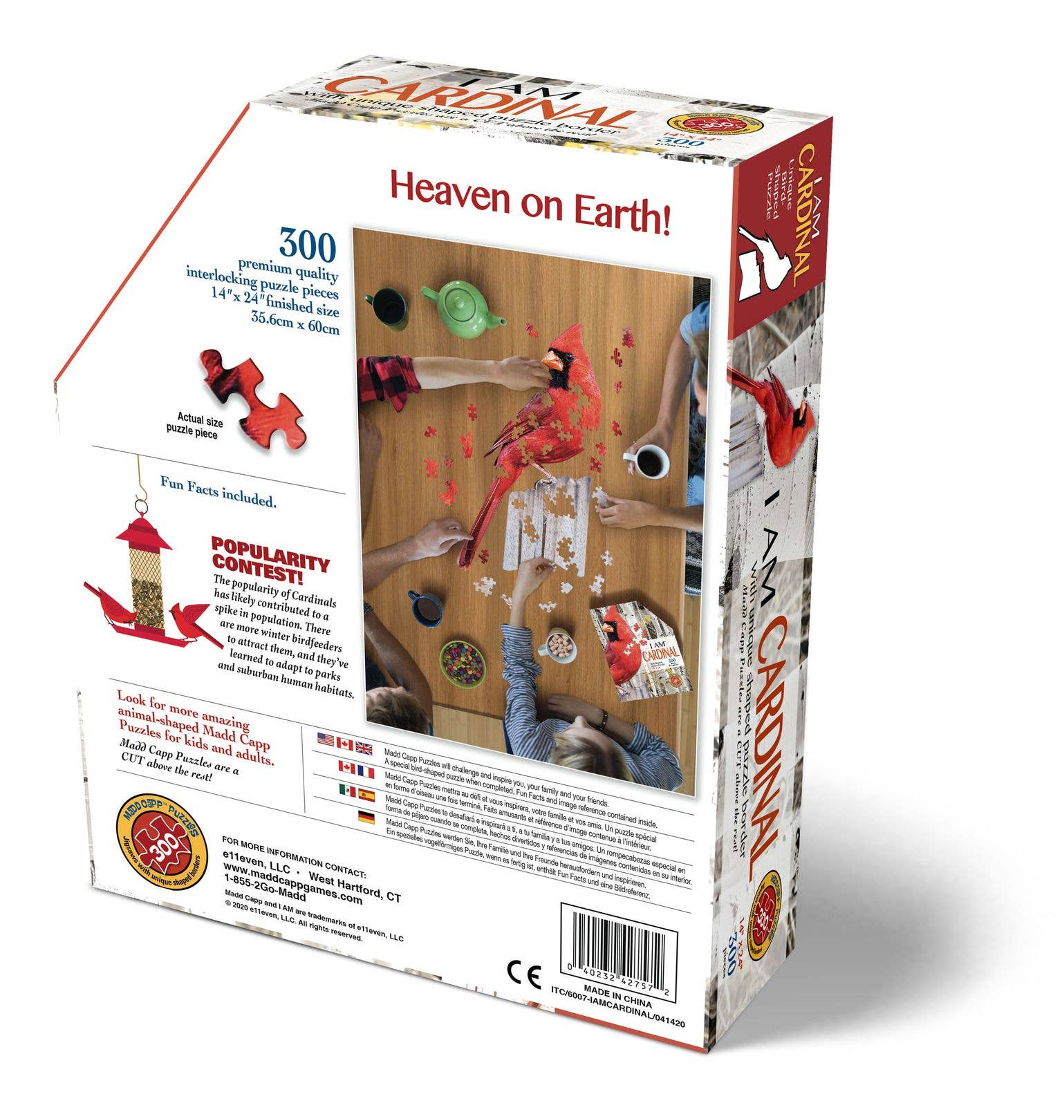 Box of the "I AM CARDINAL" 300-piece jigsaw puzzle featuring uniquely shaped pieces, a bird feeder scene, and showing people assembling the Cardinal puzzle. It prominently displays the slogan "Heaven on Earth!" along with the flags of three countries.