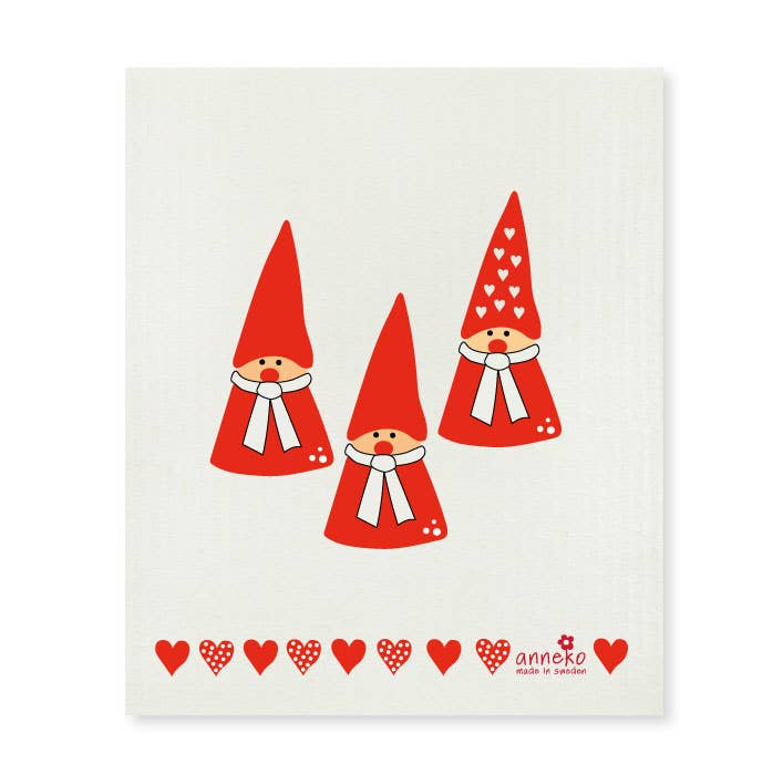 The "Dish Cloth: Three Santa" features three illustrated gnomes wearing red hats and scarves, set against a cream background. Charming red hearts line the bottom, adding a whimsical touch to the designer print. Plus, it's eco-friendly and compostable!