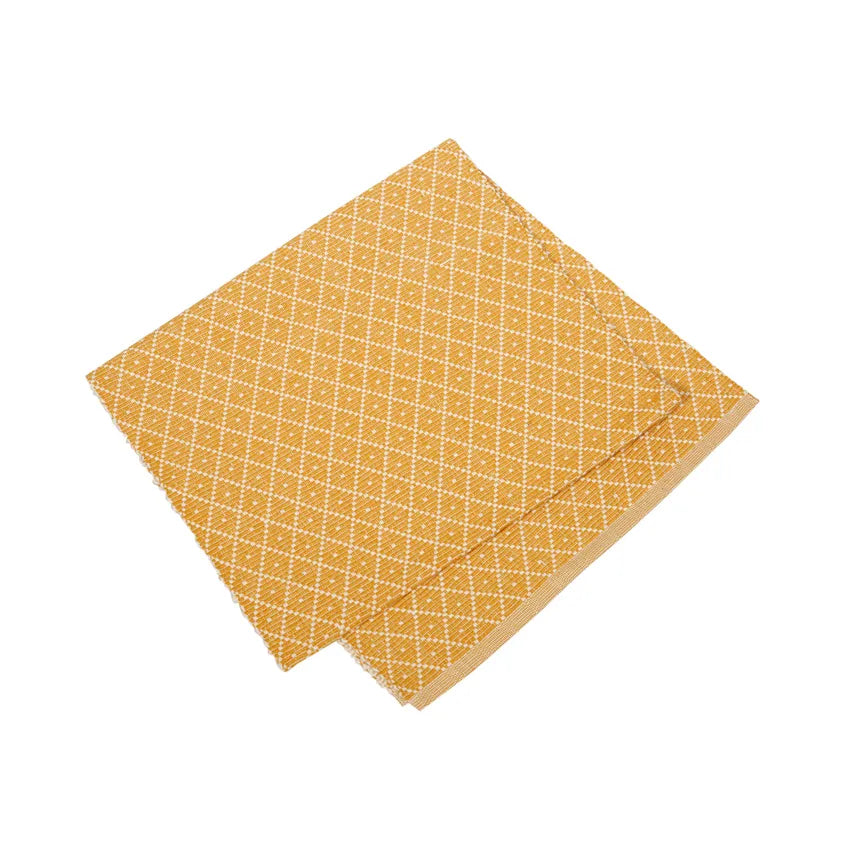 A folded yellow cloth napkin with a white diamond pattern elegantly complements the Placemat: Saffron Ella by Willie, crafted from eco-friendly recycled textiles.