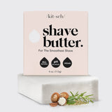 A box of KITSCH Soap: Shave Butter Solid Bar 4 oz, a luxurious natural shaving cream, rests on a white soap block with shea nuts and herbs arranged in front; the box features All Natural, pH Balanced, and Vegan highlights.