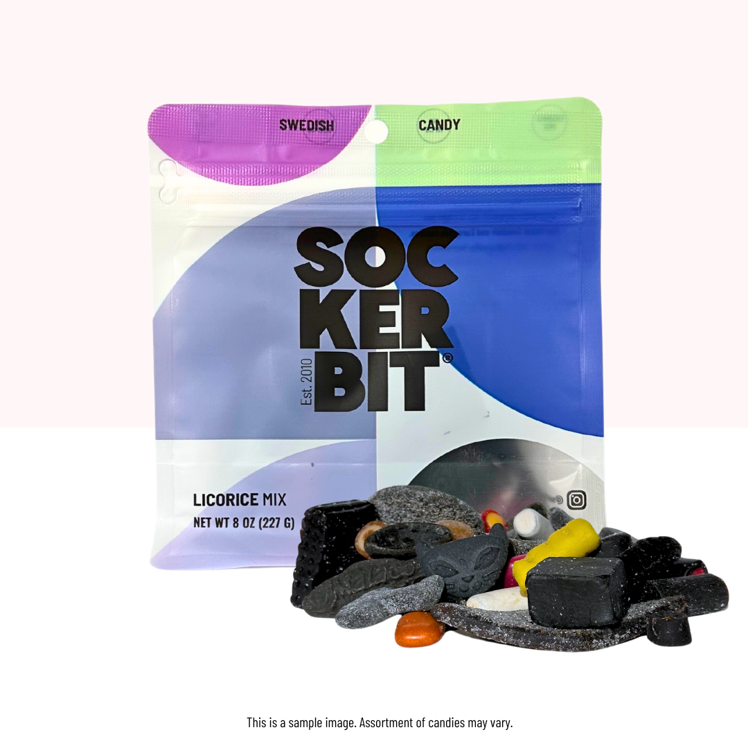 An 8oz Sockerbit Licorice Mix Swedish Candy Bag sits behind black and colorful Scandinavian licorice candies spilling out in front, highlighting the variety found in this 7-serving treat.