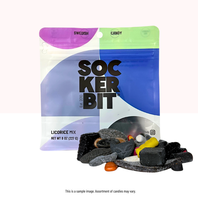 An 8oz Sockerbit Licorice Mix Swedish Candy Bag sits behind black and colorful Scandinavian licorice candies spilling out in front, highlighting the variety found in this 7-serving treat.