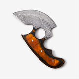 The Knife: Alaskan Ulu Style Blade features a patterned High Carbon Damascus Steel blade and an orange-brown wooden handle, shown on a plain white background.