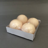 A pack of four unscented, round ivory Champagne Ball Candles (2.5" diameter) sits in a white cardboard tray wrapped in clear plastic—perfect for elegant decorative displays.