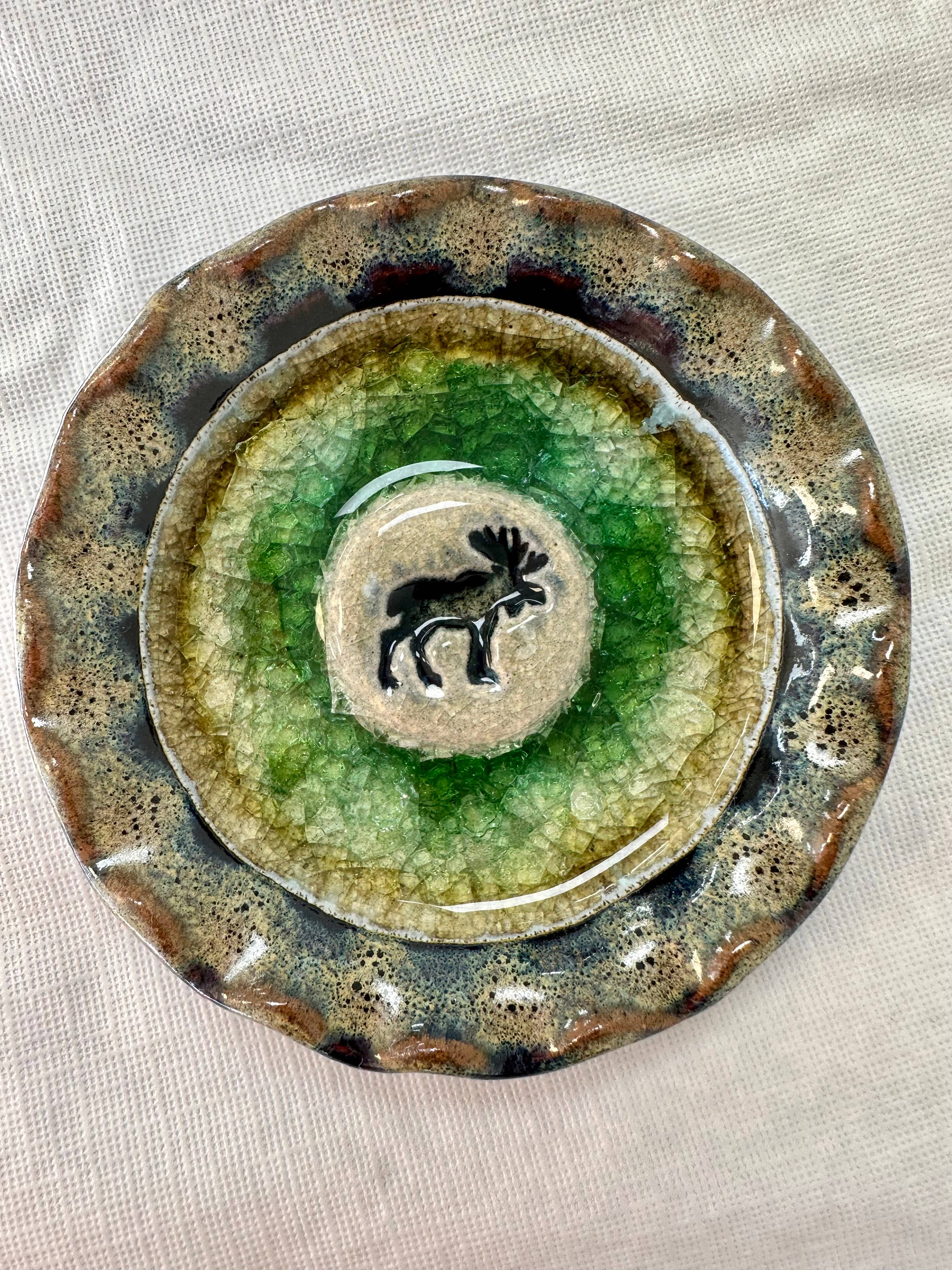 Explore the Icon Series Moose Handmade Pottery with Recycled Glass Dish, a ceramic plate with crackled glaze and earthy tones. Featuring a central moose silhouette, it embodies natural beauty and artisan charm. Each handmade piece is crafted in Colorado for unique appeal in any setting.