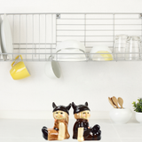 The Viking Couple Vintage Salt & Pepper Shakers, each 3" tall, sit on a white countertop beneath a dish rack with plates and cups—an ideal touch for Scandinavian kitchen decor.