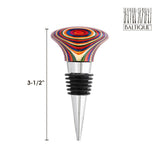 This vibrant wooden wine bottle stopper, part of the Marrakesh Collection, features a metal base and air-tight silicone rings, measuring 3.5 inches. It is decorated with the iconic Baltique logo in the upper right corner.