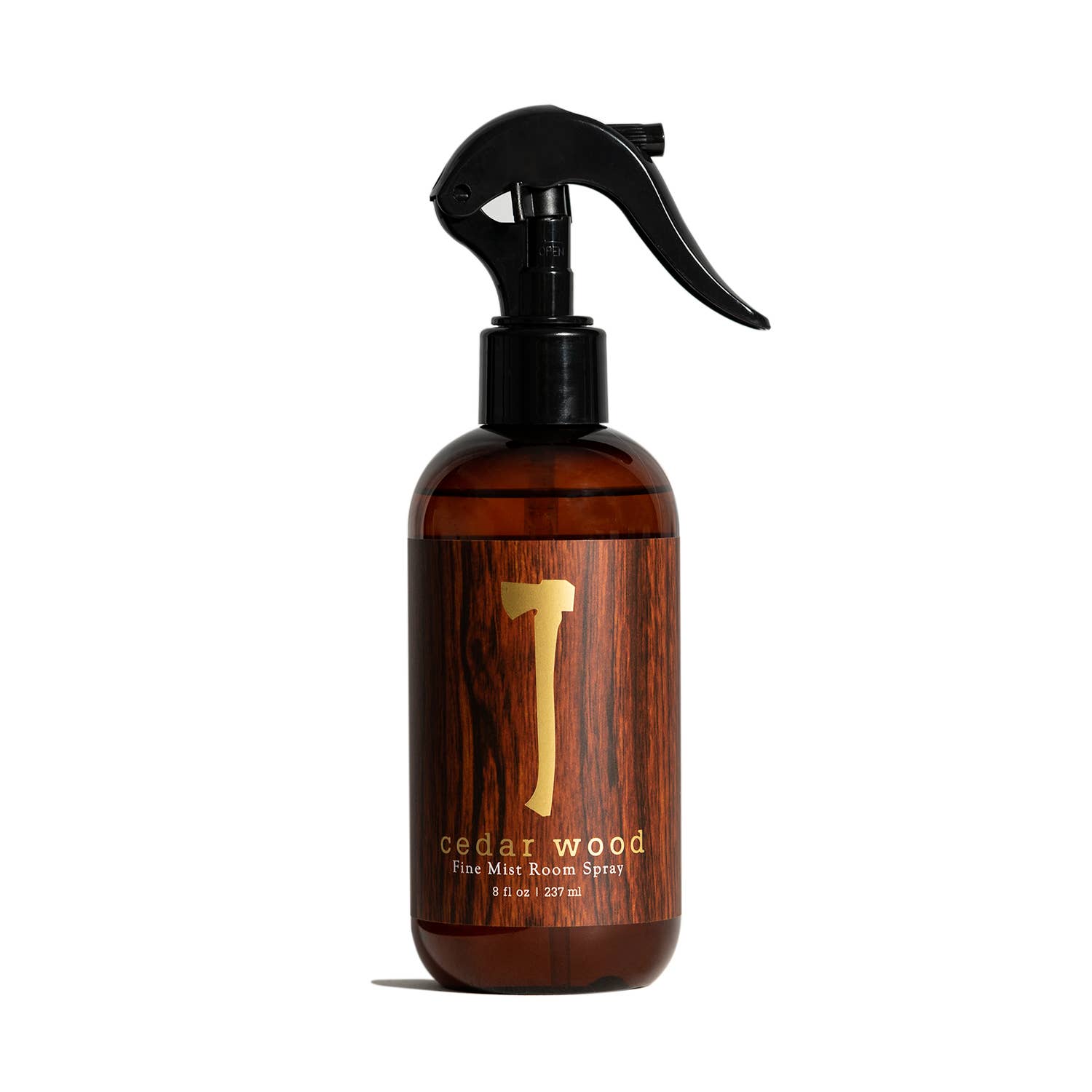 A brown spray bottle labeled "Air Freshener: Cedar Wood Room Spray" with a trigger nozzle, containing 8 fl. oz., delivers a refreshing cedar scent. This vegan and cruelty-free mist enhances any room with an inviting atmosphere.