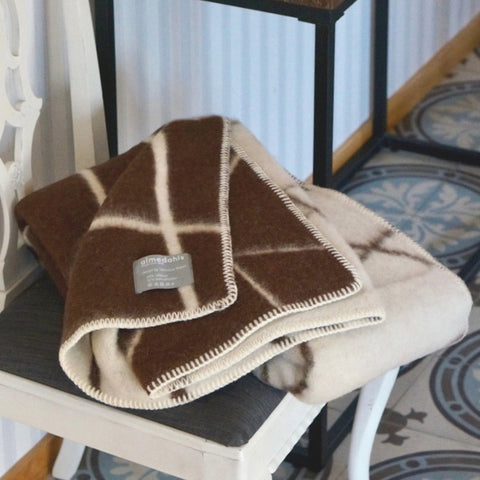 The brown plaid wool blanket used as a throw blanket on a chair.