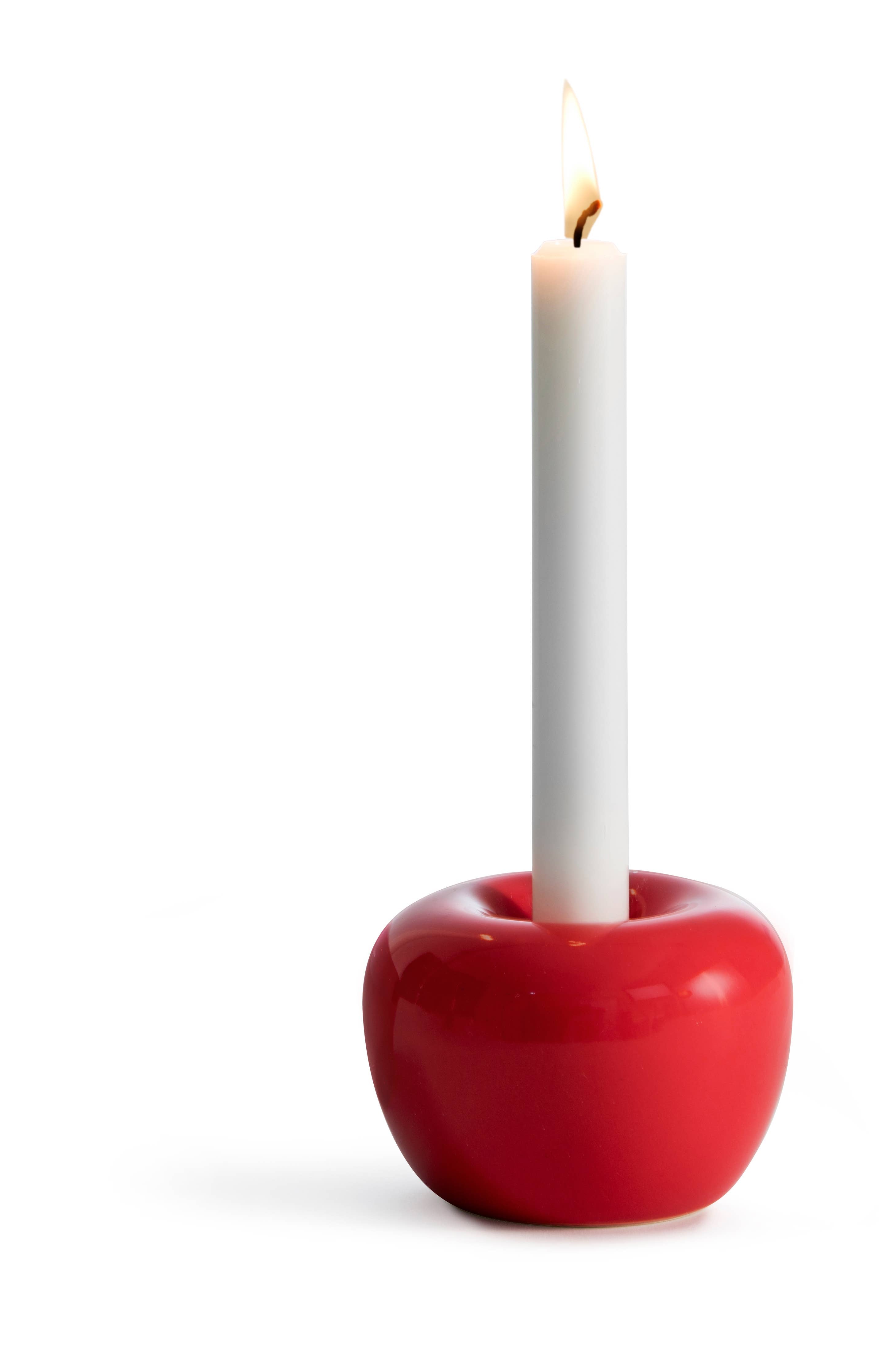 A lit white candle in the Swedish Shiny Red Apple Taper Candle Holder against a white backdrop, with the glossy red holder adding modern elegance to the scene.