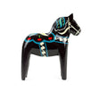 A black, hand-painted wooden Dala horse with colorful patterns stands upright on a white background.
