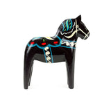 A black, hand-painted wooden Dala horse with colorful patterns stands upright on a white background.