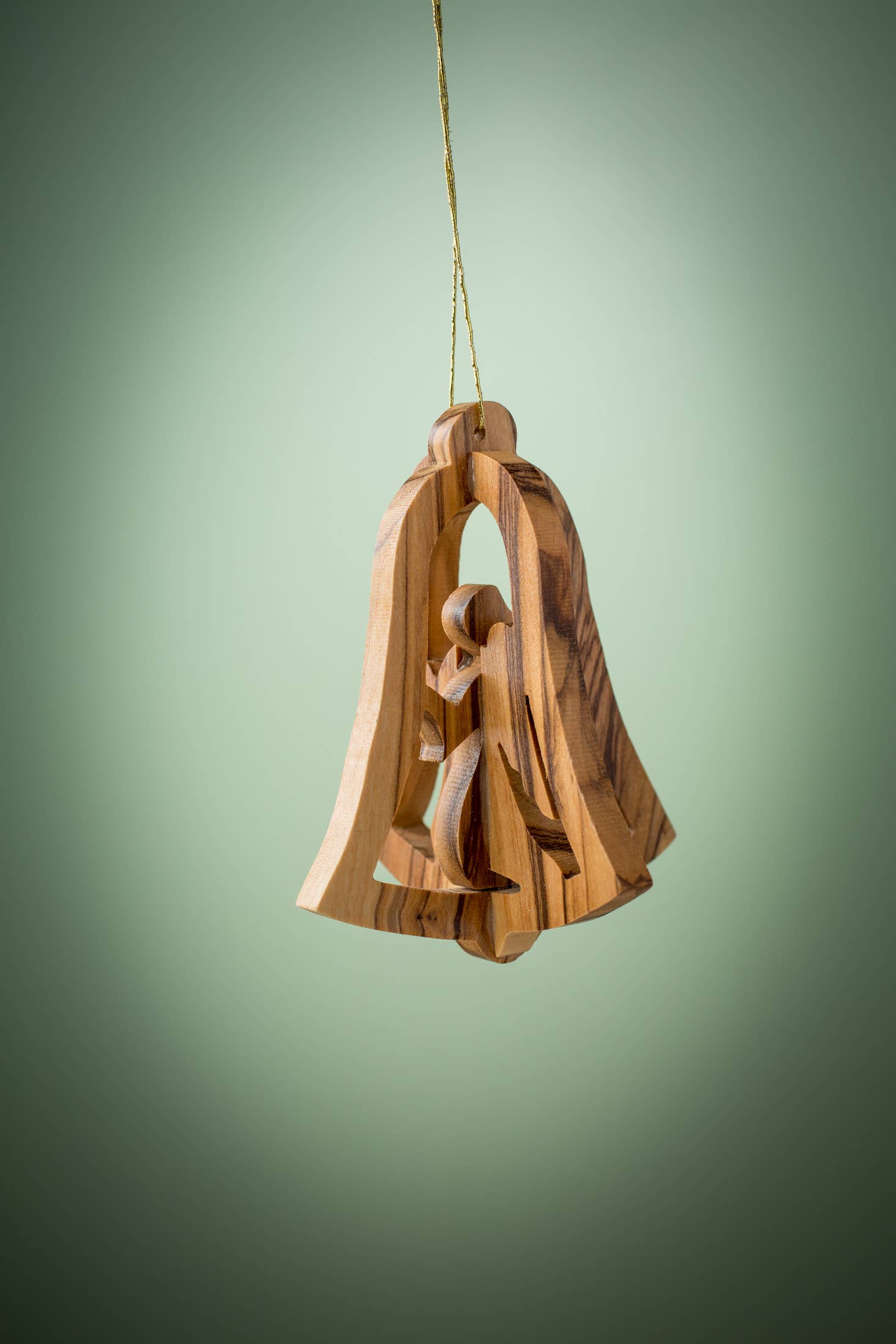 This exquisite 3D Bell with Angel ornament, meticulously crafted from Olive Wood by skilled Christian artisans in Bethlehem, showcases a beautifully carved bell with a nativity scene inside, elegantly suspended against a lush green background.