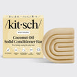 A KITSCH Coconut Oil Hair Conditioner Bar for dry, damaged hair (2.7oz) is shown next to its beige, square packaging with curved accents and various feature icons. This solid conditioner bar is specially formulated by KITSCH to deeply nourish and define kinky, curly, and coily hair types.