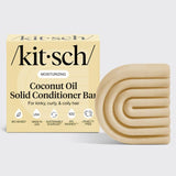 A KITSCH Coconut Oil Hair Conditioner Bar for dry, damaged hair (2.7oz) is shown next to its beige, square packaging with curved accents and various feature icons. This solid conditioner bar is specially formulated by KITSCH to deeply nourish and define kinky, curly, and coily hair types.