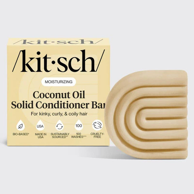 A KITSCH Coconut Oil Hair Conditioner Bar for dry, damaged hair (2.7oz) is shown next to its beige, square packaging with curved accents and various feature icons. This solid conditioner bar is specially formulated by KITSCH to deeply nourish and define kinky, curly, and coily hair types.