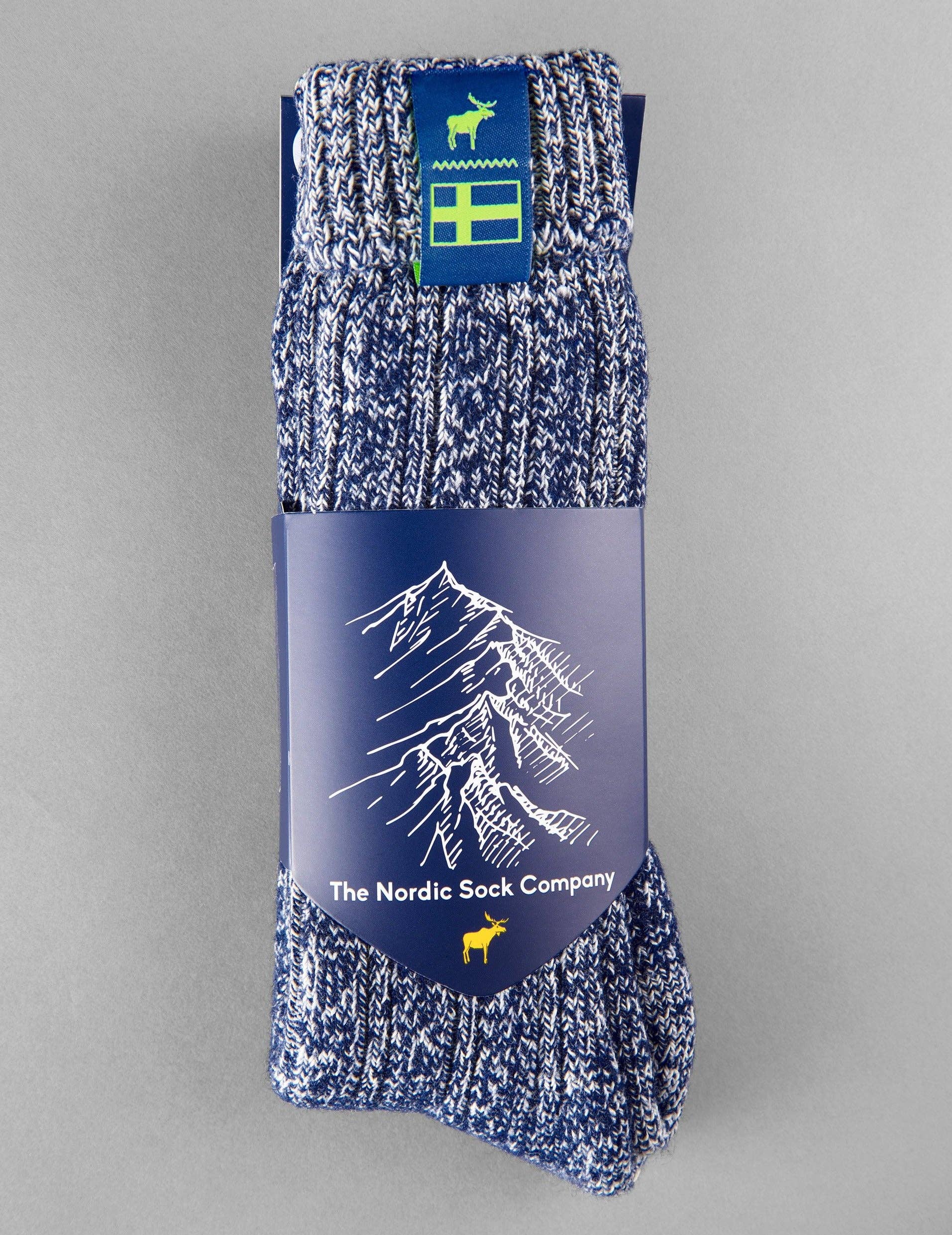 A pair of Classic Nordic Socks in Swedish Midnight Blue from The Nordic Sock Company, featuring blue and white speckles and cozy winter warmth—packaged with a mountain illustration and moose icon.