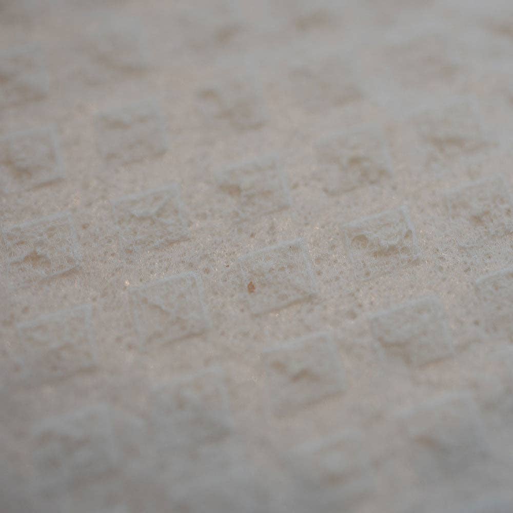 Close-up of a textured surface featuring a repeating pattern of small, raised squares, similar to those found on the "Life is Better at the Lake" Swedish Dish Cloth crafted from sustainable materials.