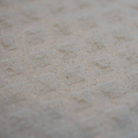 Close-up of a textured surface featuring a repeating pattern of small, raised squares, similar to those found on the "Life is Better at the Lake" Swedish Dish Cloth crafted from sustainable materials.