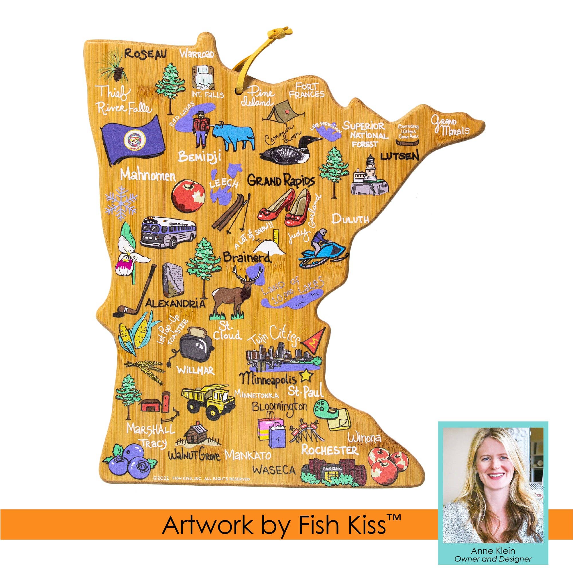 The Minnesota-shaped cutting board by Fish Kiss™ showcases vibrant illustrations of landmarks and cities, complete with colorful icons. It also features a small portrait of Anne Klein, the Owner and Designer.